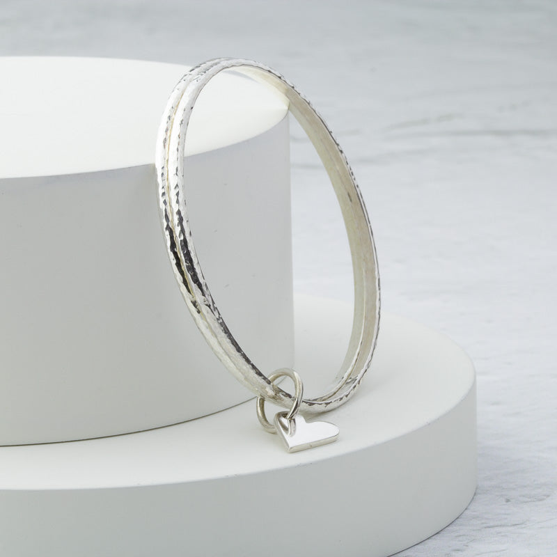 Mezza Bangle Pair of handmade solid silver hammered bangles with heart charm – Cara ...