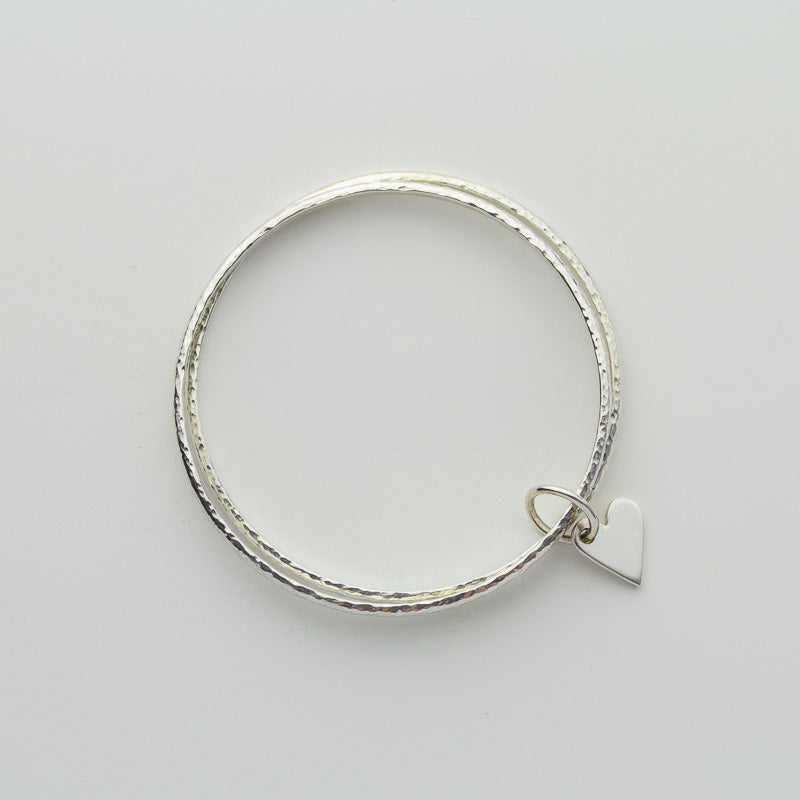 Mezza Bangle Pair of handmade solid silver hammered bangles with heart charm – Cara ...