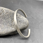 Aventis Contorno Mens Silver Cuff with D-Profile in Satin Finish Against Rock