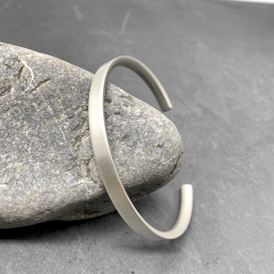 Aventis Contorno Mens Silver Cuff with D-Profile in Satin Finish Against Rock